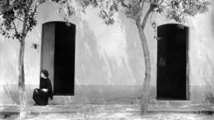 Femme assise devant maison noir et blanc film Tina modotti